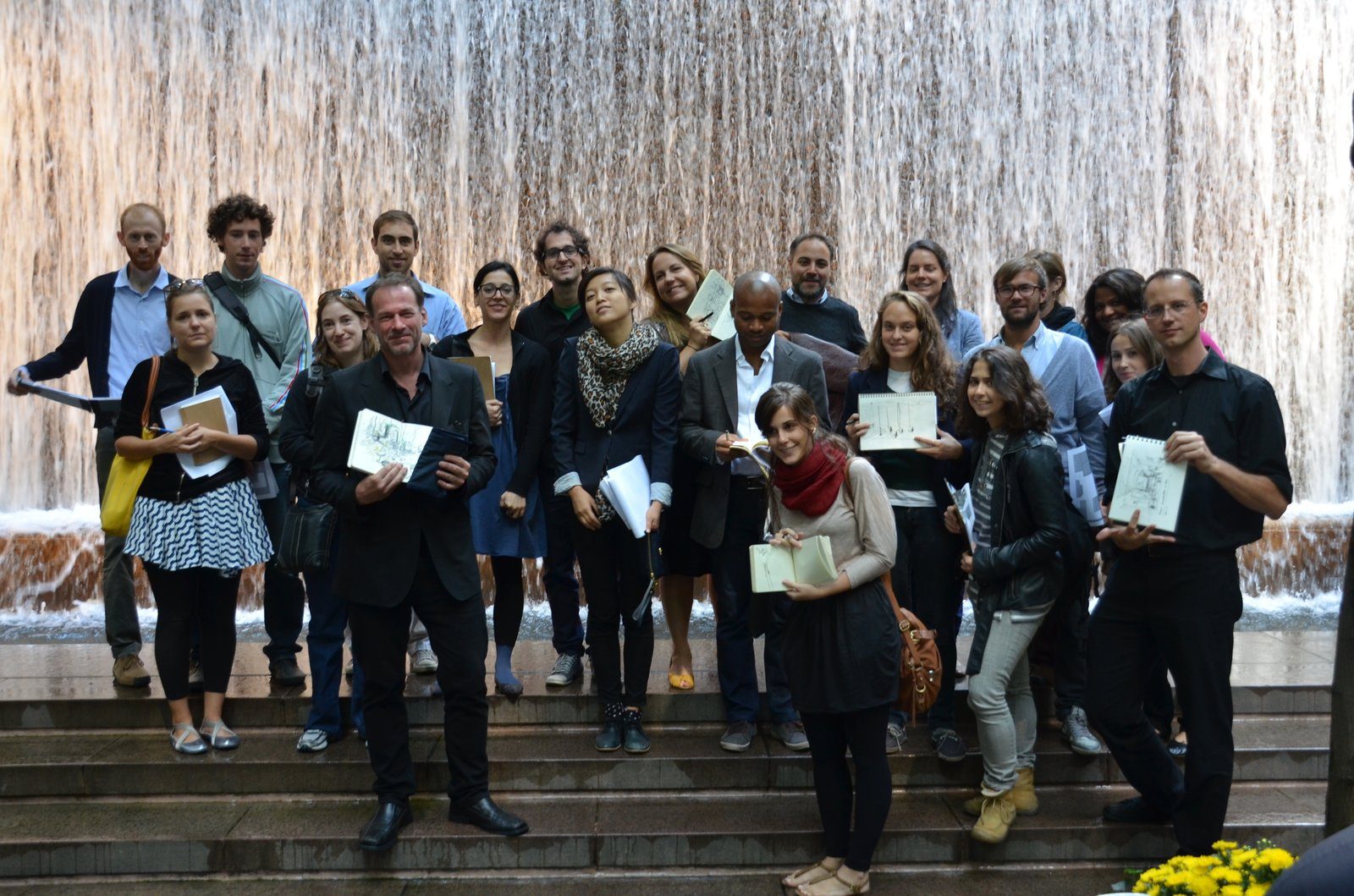 The urban design studio holding up sketchbooks beneath the waterfall wall of Paley Park, New York, around 2012